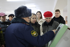 Доцент кафедры уголовного процесса и криминалистики СФУ Я. М. Плошкина и другие участники «десанта ППС» с интересом слушают рассказ заместителя начальника ИК-17 полковника А. Г. Игнатова о работе информационного терминала для осужденных